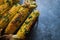 Native American cuisine, roasted corncobs with green herbs and sauce on blue marble background, close-up. Grilled corn, healthy ea