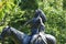 Native American Warrior on horse looking up to heaven statue among green bokeh branches in Woodward Park Tulsa Oklahoma USA 8