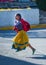 Native Indigenous girl run in traditional colorful dress on city street with a smile, Mexico, America