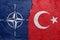 NATO and Turkey - Cracked concrete wall painted with a OTAN flag on the left and a turkish flag on the right stock photo