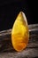 Natural amber. A piece of yellow opaque natural amber on large piece of dark stoned wood.