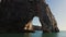 A natural arch in a limestone sheer cliff, washed by sea waters