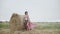 Natural beauty of elegant lady holds a bouquet of flowers and poses at haystack