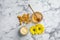 Natural beeswax, cream, honey and flowers on white marble table, flat lay