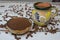 Natural bowl with ground coffee on white wooden table with organic coffee grains and Mexican cup with colorful decoration