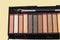 Natural brown Nude eyeshadow palette close-up, with tassel isolated on yellow pastel background