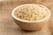 Natural brown uncooked rice in wooden bowl on burlap