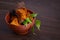 Natural Chaga mushroom pieces in a bowl with birch twig on a dark wooden background