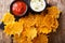 Natural cheddar cheese chips with herbs with sauces close-up on a board. horizontal top view