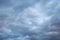 Natural color dramatic dark blue cloudy sky with wavy rippling clouds aligned above horizon, taken with wide angle 35 mm lens