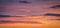 Natural color dramatic dawn or dusk sky with painterly yellow, pink and blue clouds with horizon, taken with wide angle 35 mm