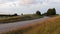 Natural color video of a countryside gravel road and a meadow around.