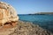 Natural copy space day shot of rocks and cliffs on an empty wild beach with the turquoise blue sea water in the background.