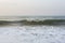 Natural copy space shot of a wave crushing on the smooth yellow sand beach surface, forming white foam, with the blue sky on the