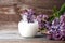 Natural cosmetics concept, skin and body care, lilac flowers in  jar with milk on wooden background with copy space