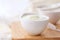Natural creamy white yogurt in cup on wooden plate