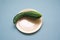 Natural cucumber of an unusual shape on a yellow plate on a blue background.