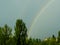 Natural double rainbow over green trees, summer city landscape