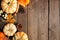 Natural fall side border of pumpkins and leaves on a rustic dark wood background