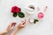 Natural floral cosmetics with rose flowers for face and body care and hands on white marble background top view