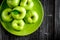 Natural food design with green apples in plate dark desk background top view