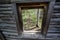 Natural frame looking to a birch tree forest through an abandoned log home window in the ghost town of Miners Delight Wyoming