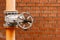 Natural gas distribution system valve in front of orange brick wall with place for text.