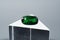 Natural gemstone green tsavorite garnet on a stand on a gray background