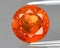Natural gemstone orange hessonite garnet on gray background