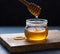 Natural golden honey drains to jar on wood background. Macro and front view