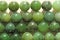 Natural green jade nephrite mineral stones beads. Green and grassy natural background made of round stone beads