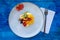 Natural and healthy fruit salad with orange set in a gourmet presentation plate on a rustic blue surface. Healthy Food Concept,