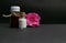 Natural Homeopathy - Close view of Homeopathic medicine bottles with pink flower buds on dark background