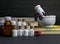 Natural Homeopathy Concept â€“ Healing herbs in a mortar and pestle next to homeopathic medicine consisting a bottle of pills-