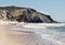 Natural lanscape of Atlantic ocean beach and group of surfers walking past sandy seaside and waves, Portugal