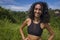 Natural lifestyle portrait of young attractive and happy hipster woman with curly hair in fitness clothes enjoying nature outdoors