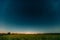 Natural Night Starry Sky Above Summer Field Meadow. Glowing Stars, Meteorite Trail And Sunset Sunrise Lights Above