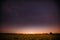 Natural Night Starry Sky Above Summer Field Meadow. Glowing Stars, Meteorite Trail And Sunset Sunrise Lights Above