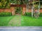 Natural orange clay brick arched wall entrance in a tropical garden with pattern of brown laterite walkway on green grass lawn