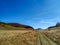 Natural path way in a big grass field surrounded by mountains in  natural serene environment landscape for a relaxing walk