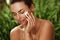 Natural peaceful portrait of a beautiful girl with pure skin doing skincare with creme outdoors