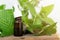 Natural peppermint essential oil in a glass bottle with fresh mint leaves on wooden background