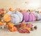 natural and pink colored crochet woolen pumpkins with autumn leaves on a wooden tray and lights