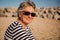 Natural portrait of active senior woman with sunglasses sitting on the beach