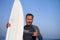 Natural portrait of attractive and happy surfer man on his 40s carrying surf board after surfing morning at beautiful beach in