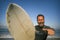 Natural portrait of attractive and happy surfer man on his 40s carrying surf board after surfing morning at beautiful beach in