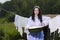 Natural Portrait of Lovely Brunette Caucasian Girl With Basin of Laundry Against Hanged Linen on Rope Behind In Countryside