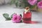 Natural pure rose oil or scented water in bottles for spa, skin care or aromatherapy. Glass bottle on a wooden table, small pink