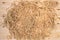 Natural raffia lies in the form of a pile of hay or straw on a light wooden surface