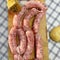 Natural raw sausage, Italian salsiccia sausage, fresh sausage on a wooden board, punch for punching the sausage before putting it